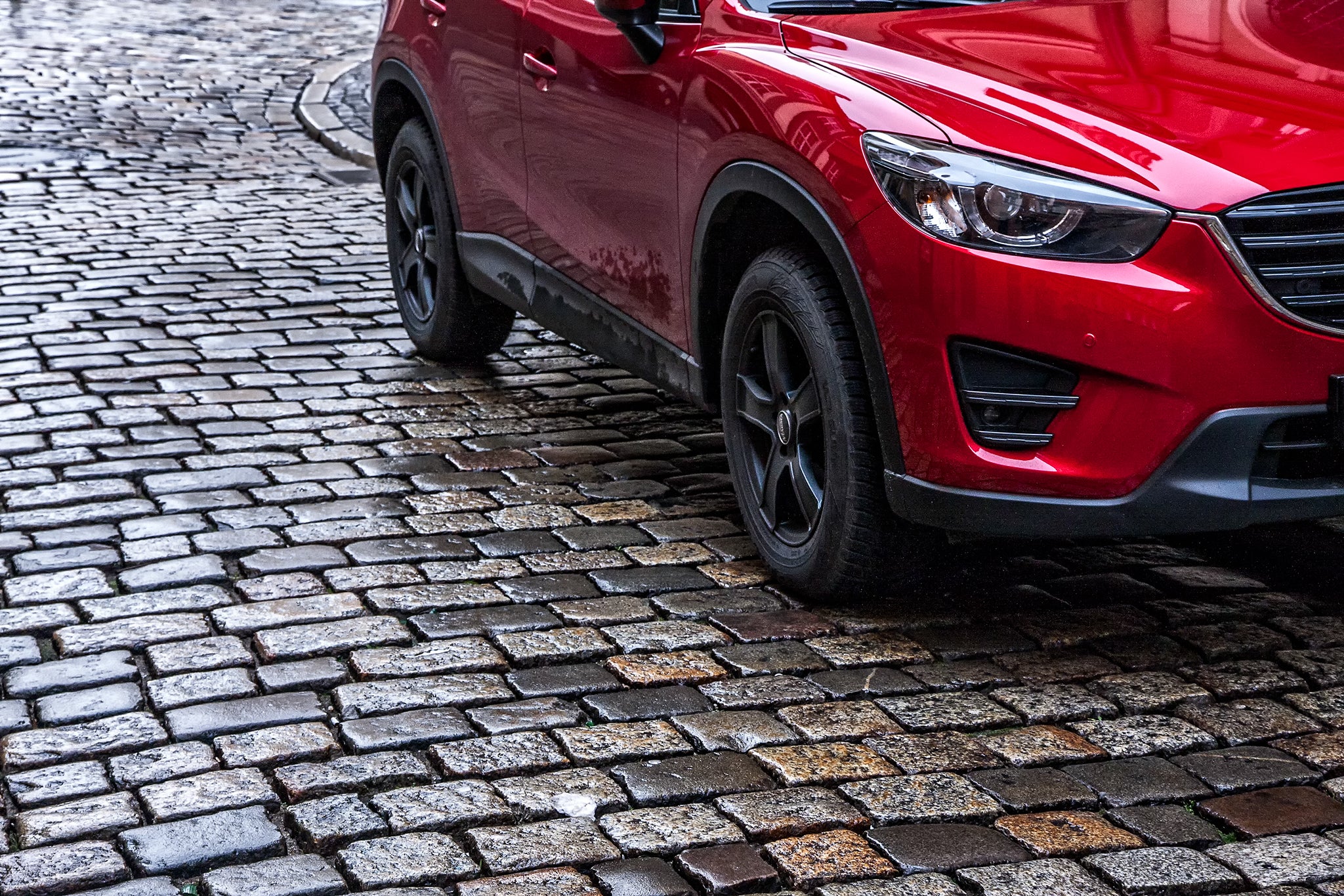 Red SUV driving A red SUV is driving on cobble stones.