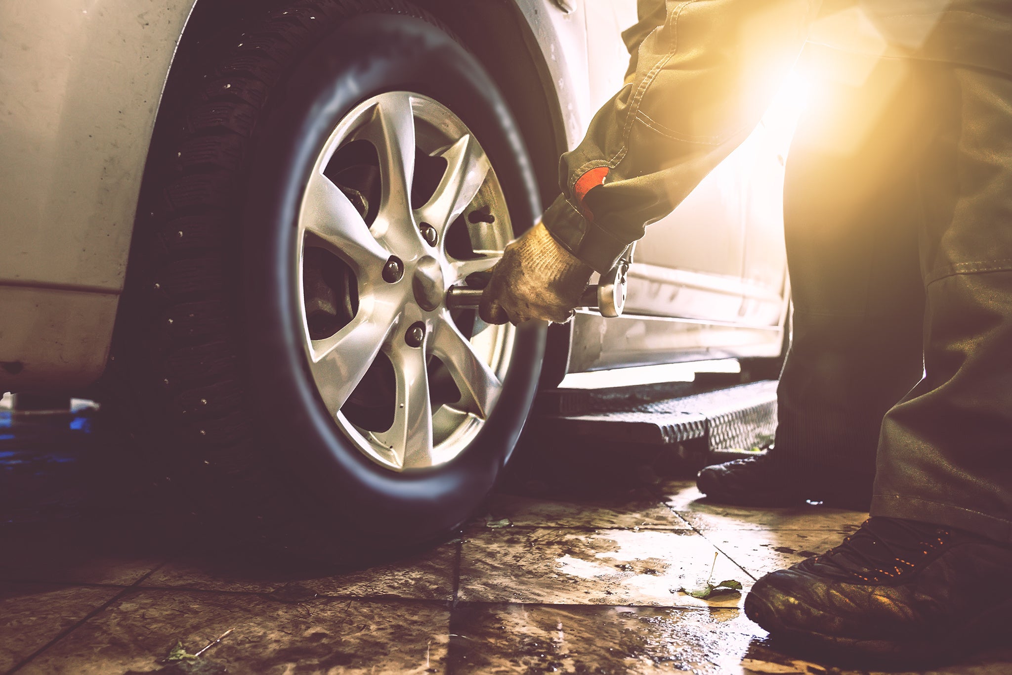 Retorquing Wheels Mechanic hands with wrench changes wheel on car with special equipment in car repair service shop, sunlight effect, toned