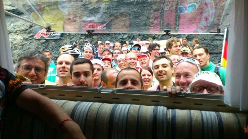 Tifosi che cercano di intravedere una TV che mostra la gara in un camper all'Alpe d'Huez, Tour De France © Meinhard Meister