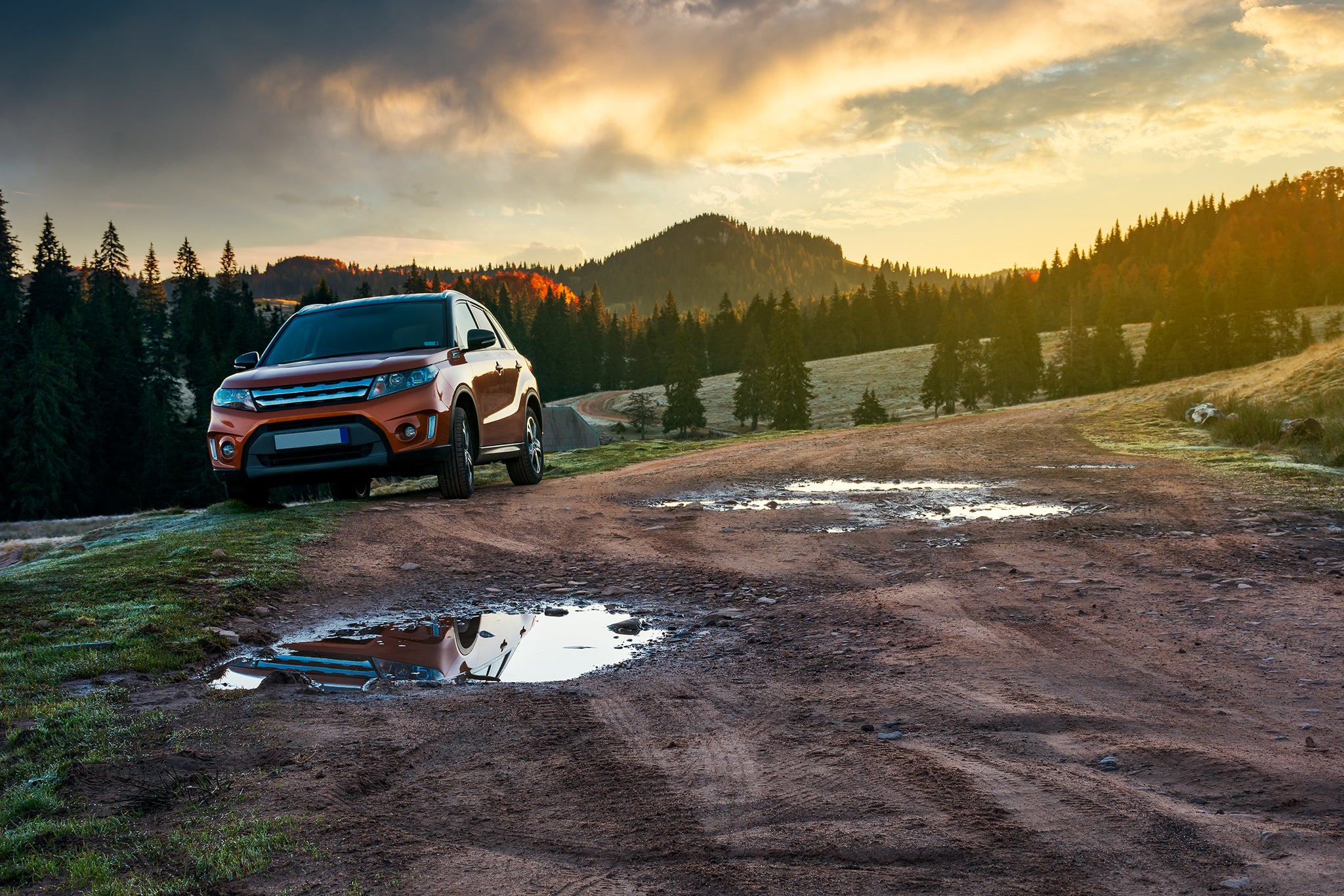 Driving in the woods Orange suv parked on the country road near forest in mountains.