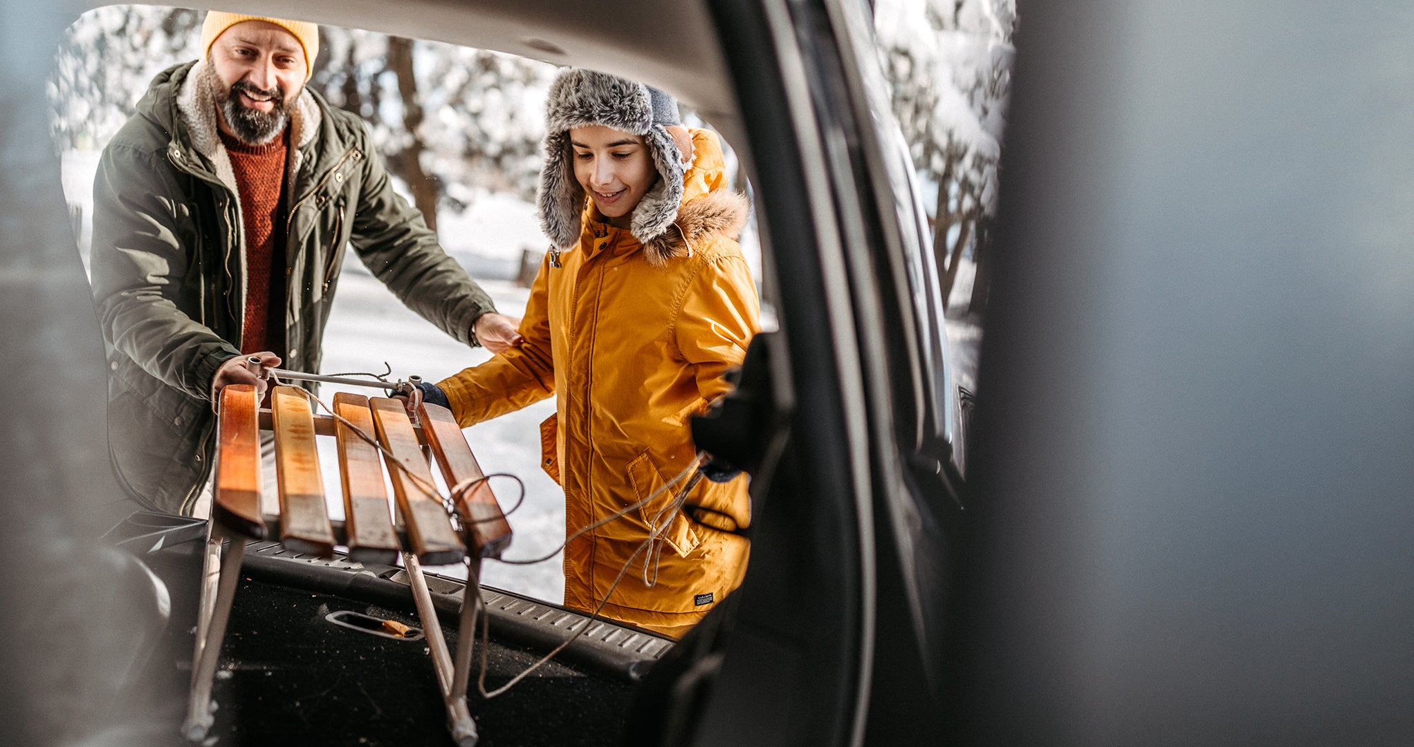 Sled in a car Father and son packing a sled for sledding in the car trunk, dressed in warm clothes.
