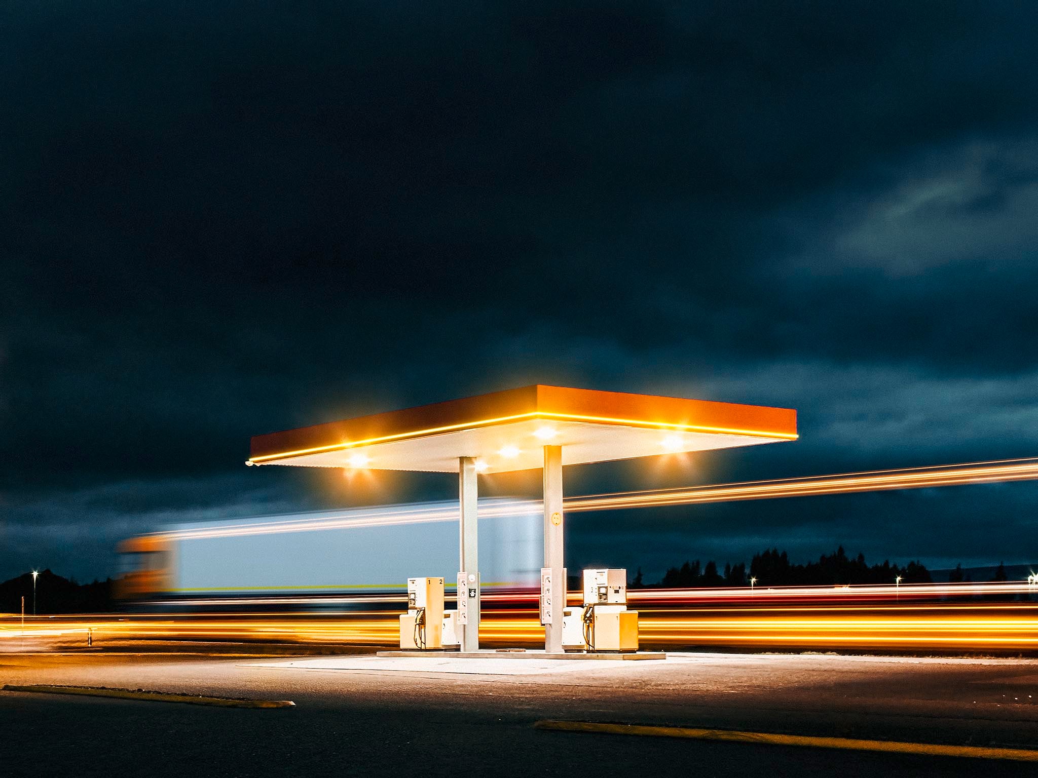 Truck passes Gas station A Truck passes a gas station during night.
