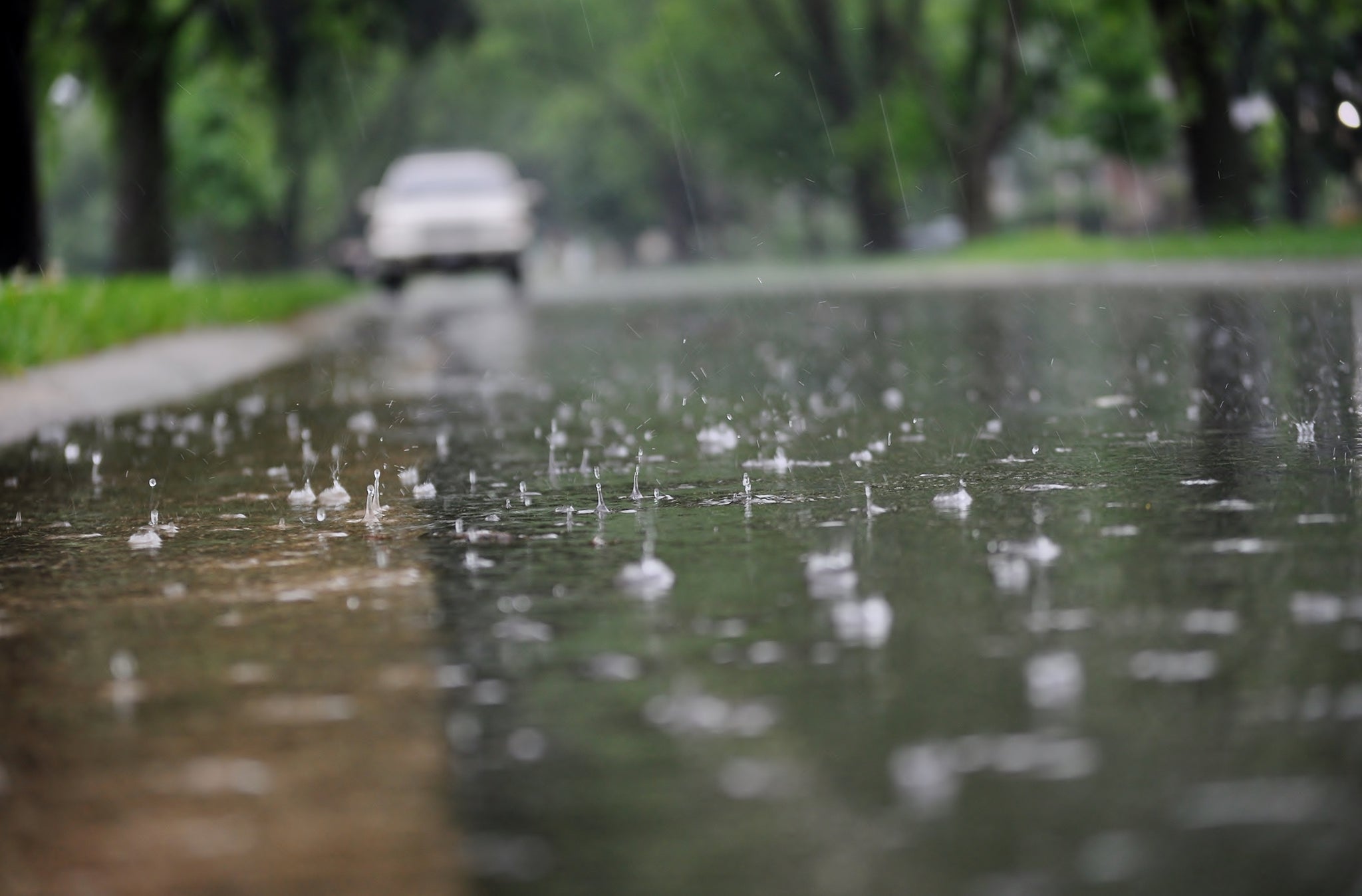 All Season tires Water flowing along the street curb during heavy rain. Close up of splashing raindrops and air bubbles.