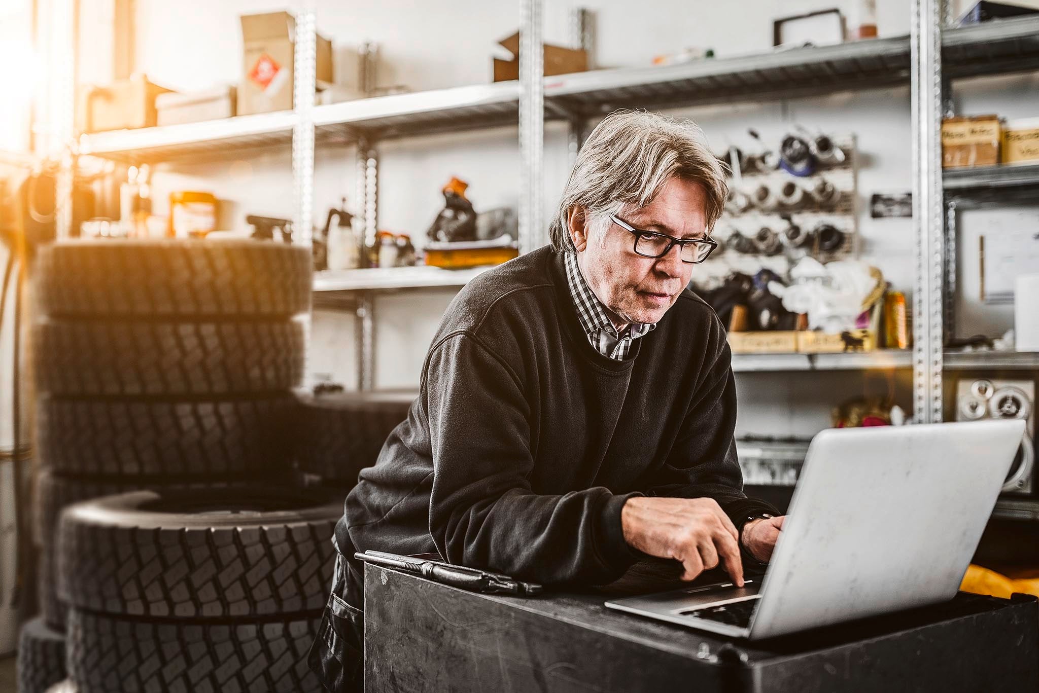Mechanic with laptop Male mechanic using laptop by shelves at tire shop